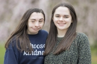 Twin sisters, including one wearing a blue sweatshirt that says Choose Kindness, are standing in front of a blurred background. Marywood Students Travel Nationally and Regionally to Give Kindness Presentations