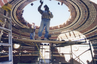 Two people work on constructing a stone dome.