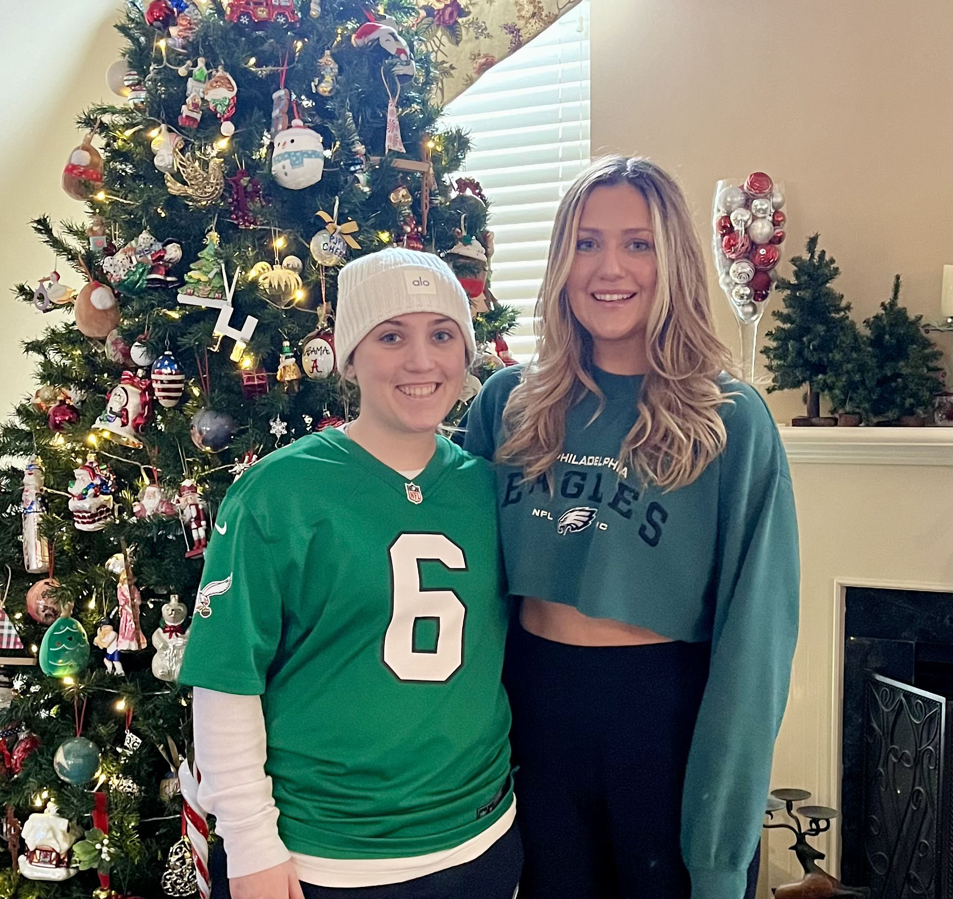 Two girls in front of christmas tree smiling at camera