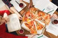 Students studying and eating pizza.