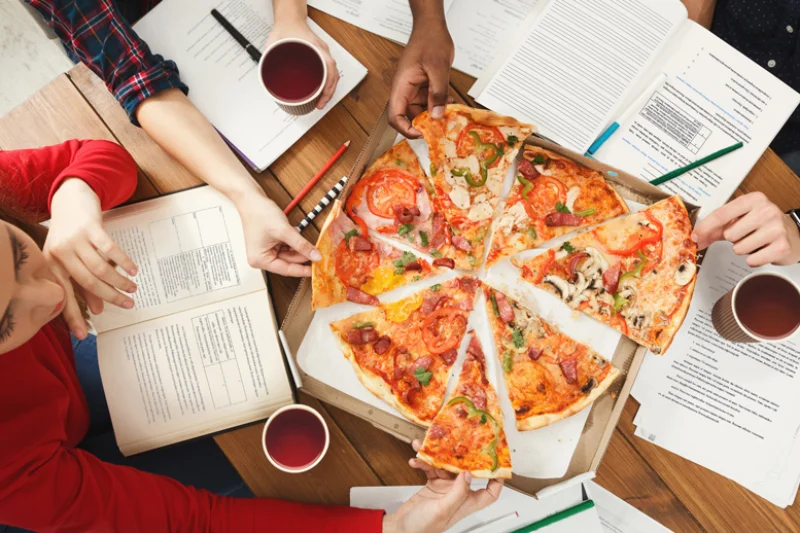 Students studying and eating pizza. Dining Tips for Marywood Students