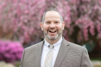 Dr. Jeff Kegolis is pictured in front of a tree with pink blossoms.