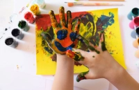 A smiley face is painted on a child's inner palm. How Art Therapy is Changing Mental Health