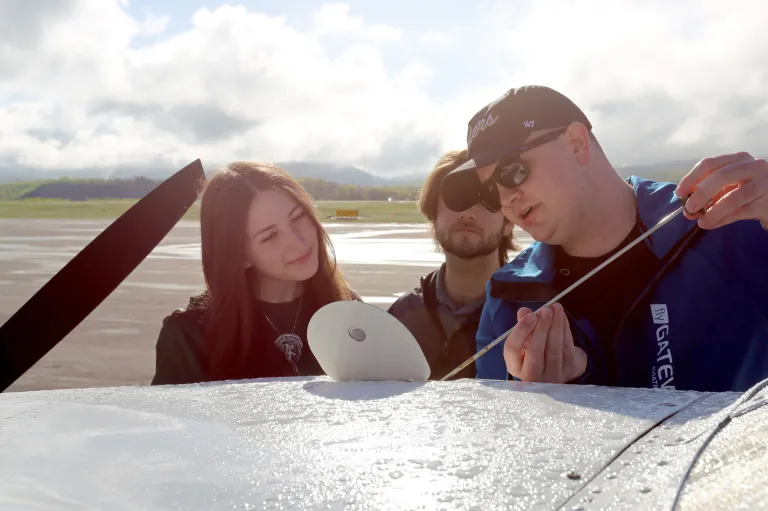 students learning how to check oil on plane with instructor showing them