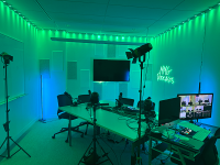 green and blue lit room with microphones, screens and lights