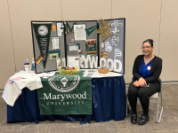 A Marywood Social Work student sitting next to a display table.