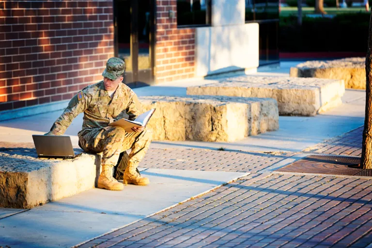 A student veteran sittimng on the curb.